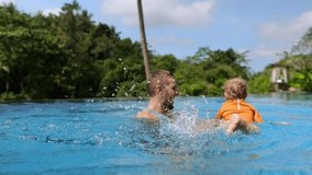 Dad and his child have fun on vacation in the pool, the father teaches his baby to swim supporting him in the water, the child flops his feet and splashes. Single father with child. Super slow - Powered by Shutterstock - Get 15% off with code: PIKWIZARD15