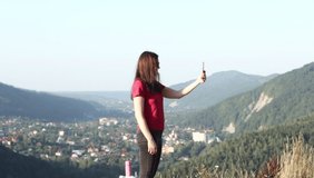Young woman shoots video on smartphone beautiful mountain city and valley. Girl Standing in Nature Scenic and Natural Filming via Panoramic Hold Smartphone Camera.