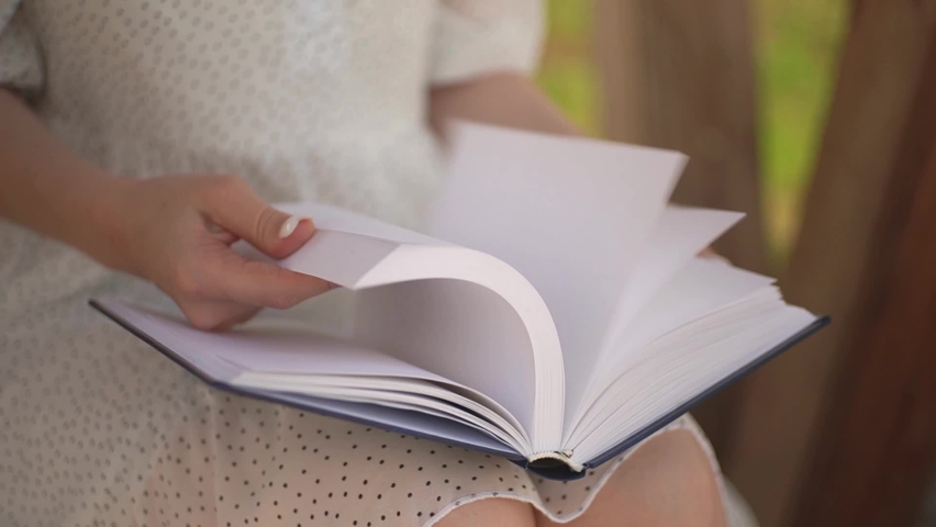 girl leafing through a book with blank pages