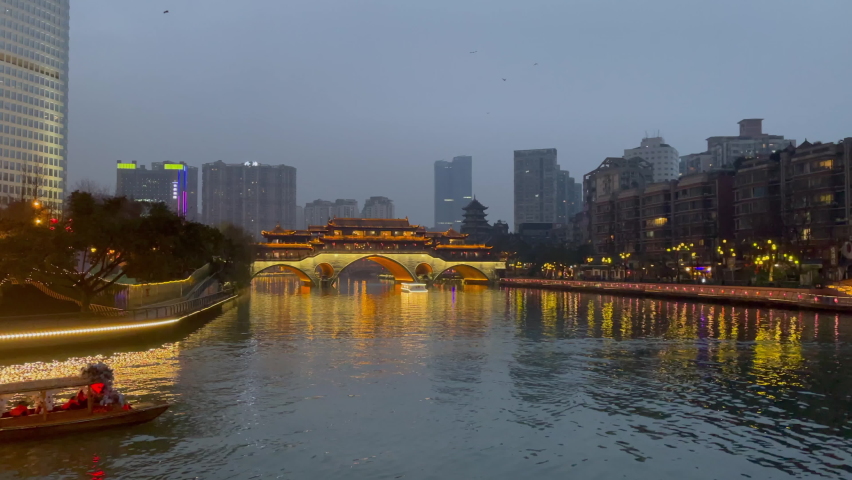 Little tour boat with red lanterns crosses the Jinjiang River to see the iconic landmark, the Anshun Bridge in Chengdu, Sichuan, China