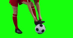 Video of caucasian female football player tying shoelaces and copy space on green screen. Female football, female sports and competition concept.