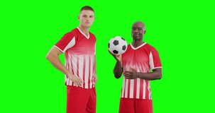 Video of two diverse male soccer players with ball on green screen background. Soccer, football, sports and competition concept.