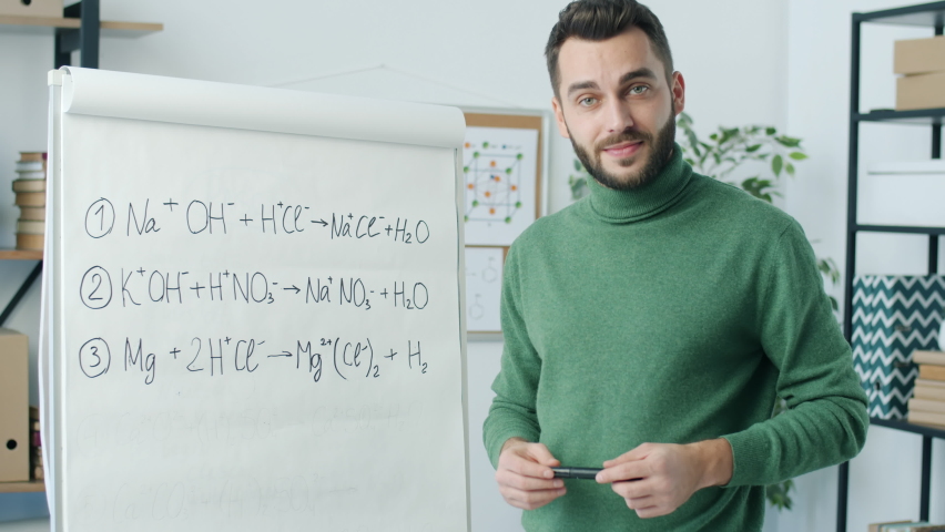 Chemistry professor writing formula on board speaking and looking at camera giving distant lesson. Modern education and science concept. - Powered by Shutterstock - Get 15% off with code: PIKWIZARD15