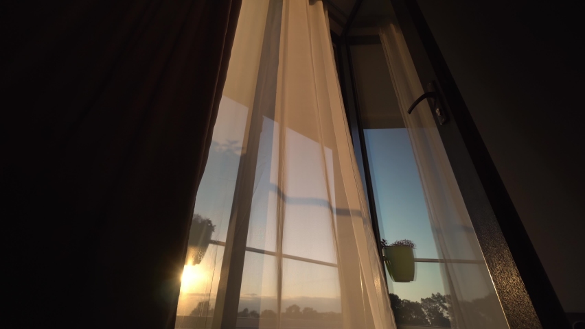 In setting sun, transparent fluttering curtain in room develops by window on balcony in cells. romantic mood and spring weather. ventilation of premises. fresh wind. Royalty-Free Stock Footage #1093567207