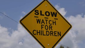 Yellow Slow Children at Play Road Sign and road. Traffic signs or road signs are signs erected at the side of or above roads to give instructions or provide information to road users - Powered by Shutterstock - Get 15% off with code: PIKWIZARD15