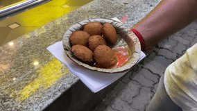 Video of a man holding special Yellow Split Gram Fritters, Mungdal Bhajiya, Pakoda, Dalwada, Pakora, or Moong Dal Vada served with Green Chutney.