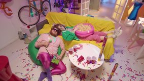 High angle shot of drunk couple in bright trendy outfits sleeping in messy room with colorful neon light after party - Powered by Shutterstock - Get 15% off with code: PIKWIZARD15