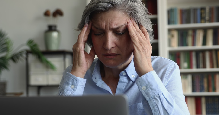 Tired overworked hoary mature lady touching face, rubbing temples, having headache, bad eye sight. Annoyed angry mature lady speaking about computer, software, online app work problems | Shutterstock HD Video #1093573511