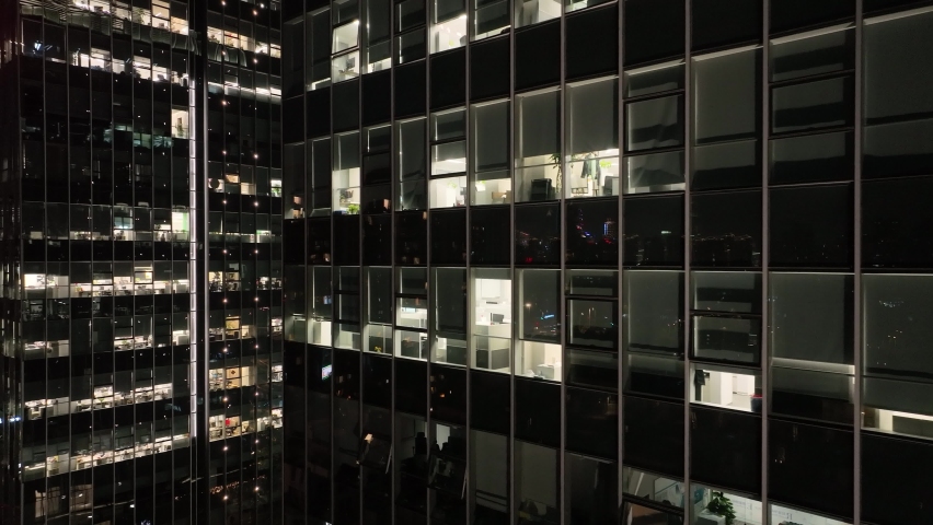 Office buildings with lights in the city downtown. Drone aerial view. People working in office building in the night, building lights in the night . Economy business cityscape concept b-roll footage.