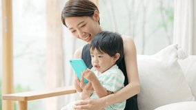 Asian boy and mother using a smart  phone in the room.