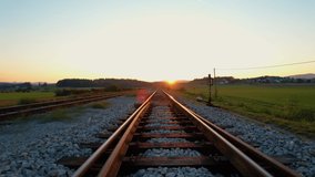 LOW ANGLE: Moving above glowing golden lit railroad tracks in autumn morning. Countryside railway passing gorgeous hilly landscape. Overview of railway tracks and junction near train station. - Powered by Shutterstock - Get 15% off with code: PIKWIZARD15