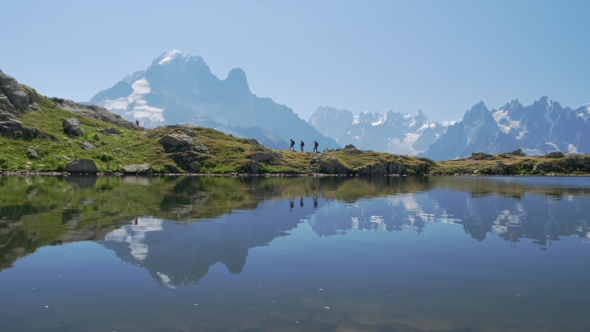 people hiking by the lac blanc with reflections of the mountains, in the valley of chamonix, in france in a sunny day. Static shoot.