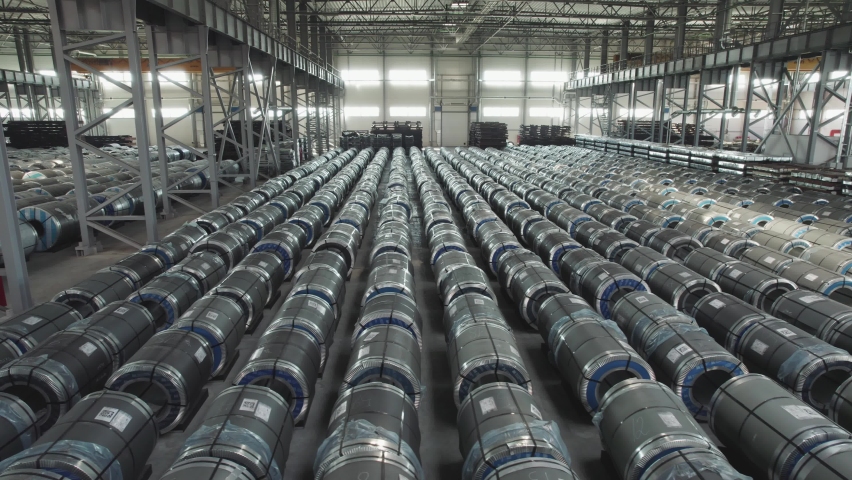 Industrial warehouse of a metallurgical enterprise. Rolled metal products are stored in rows in a warehouse. Royalty-Free Stock Footage #1093592641