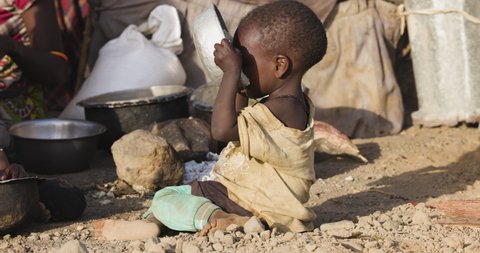 Close-up.Malnourished child due to extreme poverty, drought and climate change. Eating and drinking maize porridge in front of her dwelling. Kenya : vidéo de stock
