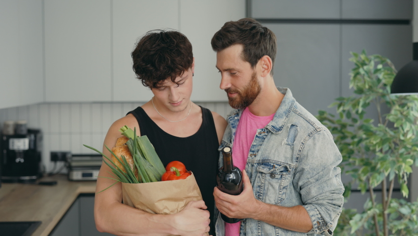 Close up of the loving lgbt couple of men came from the grocery store to home with shopping looking smiling to the camera together. People relationship and pride freedom concept