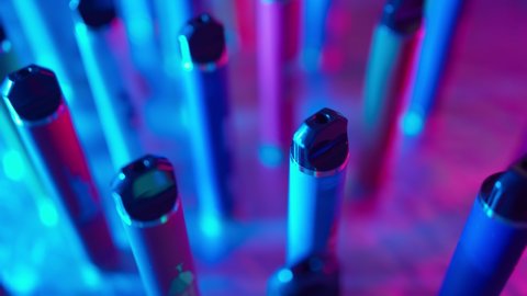 Lots of E-Cigarettes and Vapes with Smoke in Neon Lighting. Concept of Bad Habits. Modern Smoking Electronic Cigarettes. Slow Motion Video Stok