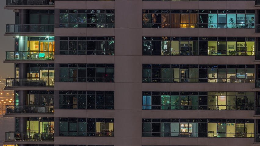 Windows lights in modern apartment buildings timelapse at night. Multi-level skyscrapers with illuminated rooms inside