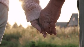 Close up unrecognizable of hands of elderly old people with wrinkles. Married couple of old people holding hands. Helping hand and support, feeling of love. Summer evening in park against sunset rays - Powered by Shutterstock - Get 15% off with code: PIKWIZARD15