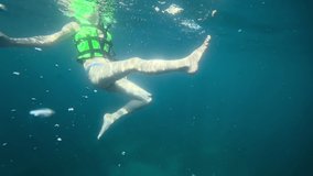 Shooting underwater, woman swims in the azure opensea. Life jacket water safety