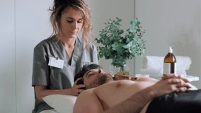 Video of female physiotherapist working examining treating injured back of male patient while doing the rehabilitation therapy pain in clinic.