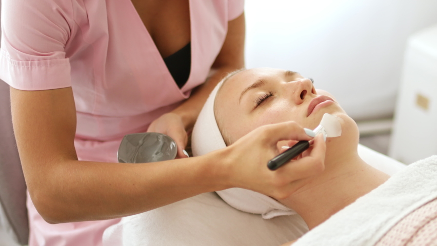 Beautician cosmetologist applies cosmetic product gel peeling mask with spatula, professional procedure in a beauty clinic salon for client. Skincare and cosmetology spa concept. | Shutterstock HD Video #1093608479