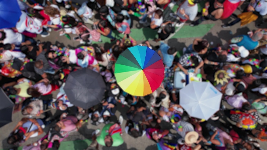 Isolated Rainbow umbrella in middle of a big crowd of people celebrating pride on city streets - Aerial view