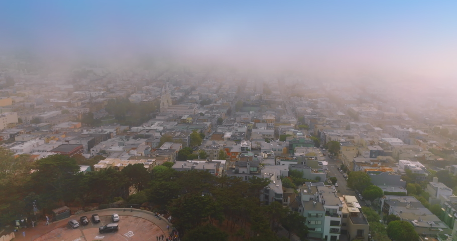 Flying over the residential area of beautiful San Francisco at sundown. Thick fog covering quickly the city. Top view.