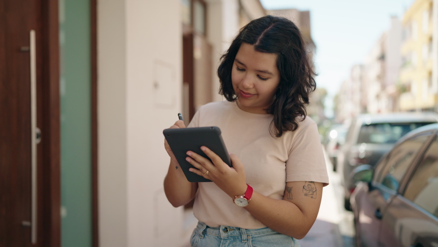 Young woman smiling confident drawing on touchpad at street