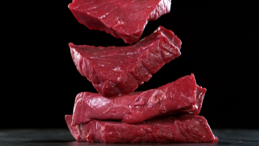 Close-up of falling tasty raw beef steaks, super slow motion, filmed on high speed cinematic camera at 1000 fps.