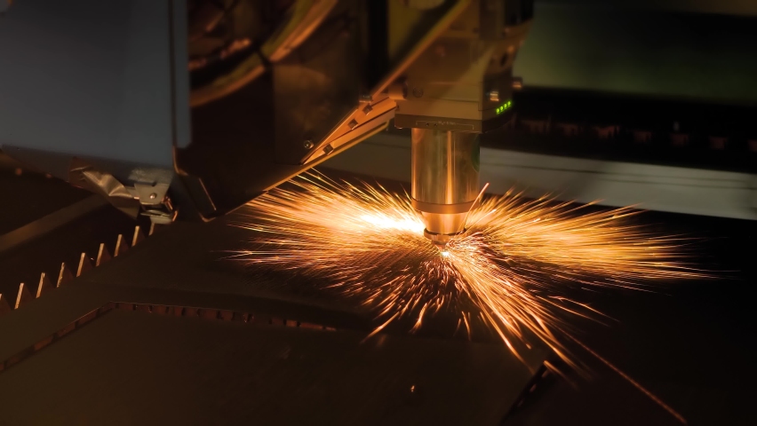 Automatic cnc laser cutting machine making holes in sheet metal with many sparks at factory, plant. Manufacturing, metalworking, industrial, technology and equipment concept