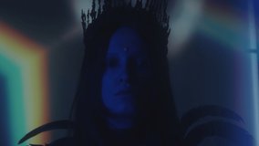 Portrait of woman with face gem wearing gothic crown and feather dress posing in dark studio with neon light and rainbow projection - Powered by Shutterstock - Get 15% off with code: PIKWIZARD15