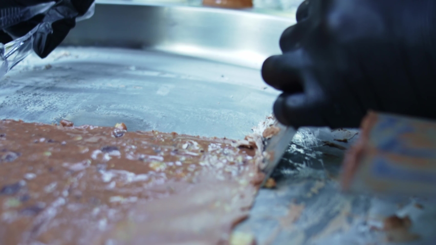 Gloved hands make roll ice cream for an outdoor party. a refreshing sweet dish made from natural fresh fruits and berries with the addition of sugar syrup.