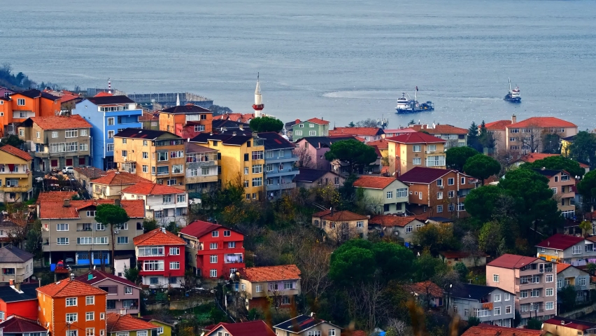 Life and ships, maritime traffic on the shores of an island with traditional and modern houses. Ferries sail along bosphorus. Endless rows of houses and majestic mosques. İstanbul, Turkey.