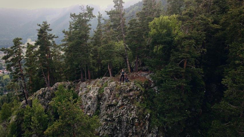 Young female adventure hiker reaching top of wild viewpoint, aerial view