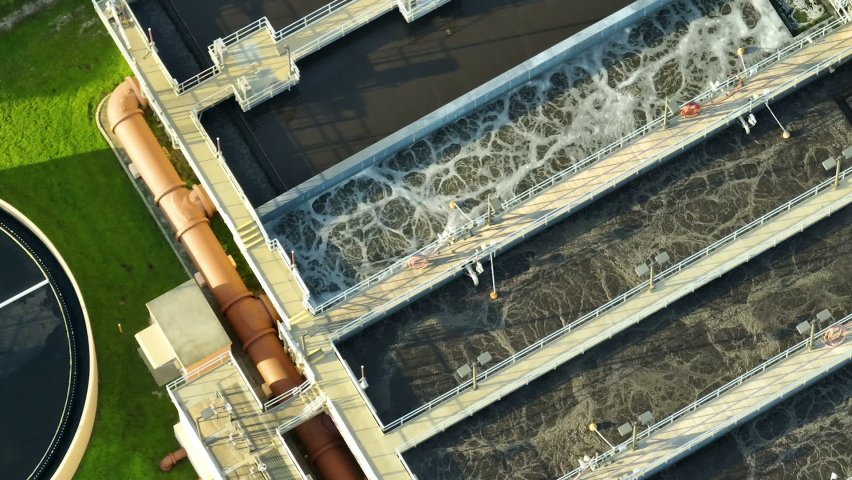 Aerial view of modern water cleaning facility at urban wastewater treatment plant. Purification process of removing undesirable chemicals, suspended solids and gases from contaminated liquid | Shutterstock HD Video #1093651959