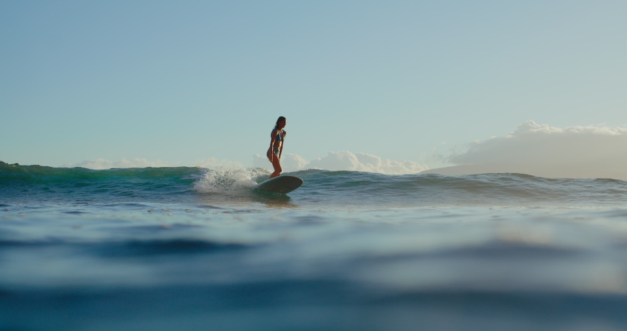 Woman surfing, riding waves on tropical island at sunset, living the dream, epic sunset surf session