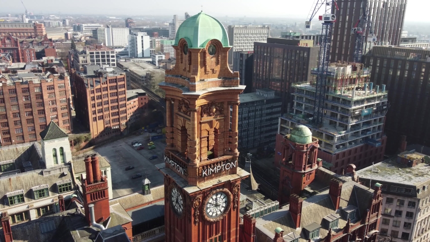 Aerial drone flight around the clock tower of the Refuge Building on Oxford Road in Manchester City Centre showing a view of the surrounding rooftops and new building being constructed. Royalty-Free Stock Footage #1093655929