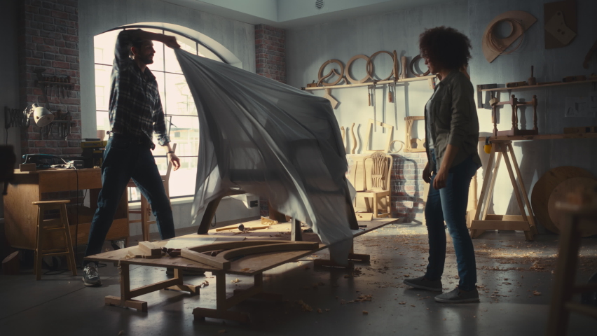 Carpenter Unveiling His New Armchair Design to a Friend, Colleague or Client. Craftsman Removing the Cover from a Luxurious Modern Lounge Chair. Excited Small Business Owners in Woodworking Workshop.