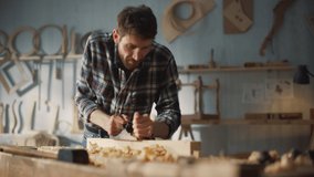 Handsome Young Artisan Craftsman in Checkered Shirt Using Hand Plane to Shape a Wood Bar. Carpenter Working on a Project in a Loft Studio with Tools on Walls. - Powered by Shutterstock - Get 15% off with code: PIKWIZARD15