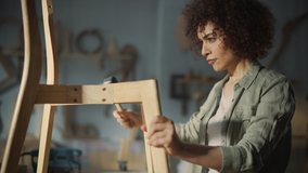 Close Up Portrait of a Furniture Designer Writing Down Dimensions and Assembling Legs of a Wooden Chair. Stylish Black Female Carpenter Working in Studio in Loft Space with Tools on the Walls. - Powered by Shutterstock - Get 15% off with code: PIKWIZARD15