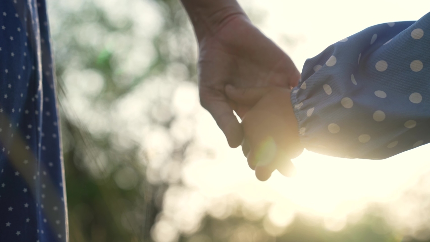 Happy family. Mom holds her daughter by hand. Family outdoors in the park. Mom in the natural forest holds the child by the hand. Happy daughter takes mom by the hand. People palms close-up. Sun