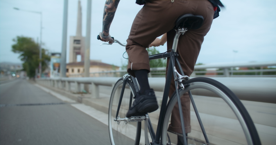 Close up on rear wheel of commuter bicycle. Young man pedal on simple single speed bike on way to work. Student ride his bike on way to school or university. Commuting in big city | Shutterstock HD Video #1093669689