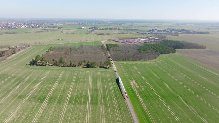 Aerial drone flight over a moving rotor blade of a windmill in a wind farm. Drone pan up