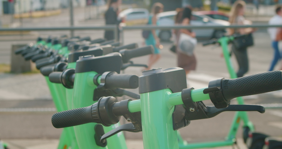 Rent an electric scooter in the city at common ecological transport parking lot. Man rents an electric scooter to ride around the city. Close-up of a man renting an electric scooter using a mobile