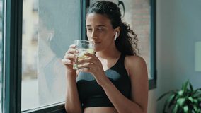Video of sporty woman drinking detox water while taking a break of doing exercise in living room at home.