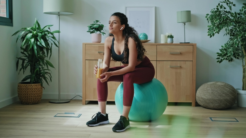 Video of sporty young woman drinking detox juice while doing exercise with the ball at home. Royalty-Free Stock Footage #1093680227