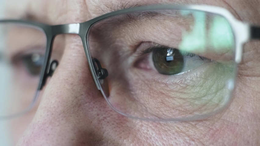 A man with glasses looks at a computer monitor. The eyes of an elderly man in close-up glasses. Close-up of men's eyes. | Shutterstock HD Video #1093683015