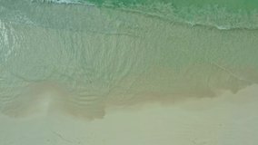 Aerial view of a sandy beach on the coast of the Indian Ocean. Abstract video of waves breaking on the sand on the shore. High quality 4k footage