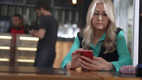 Senior female executive woman using smartphone at coffee shop. Undecided older person browsing internet online seated at cafe place restaurant - Powered by Shutterstock - Get 15% off with code: PIKWIZARD15