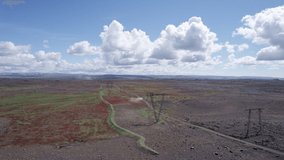 Aerial view flying on barren desert wilderness with red and green field, high voltage pole and gravel road in remote uninhabited area at highlands of Iceland - Powered by Shutterstock - Get 15% off with code: PIKWIZARD15